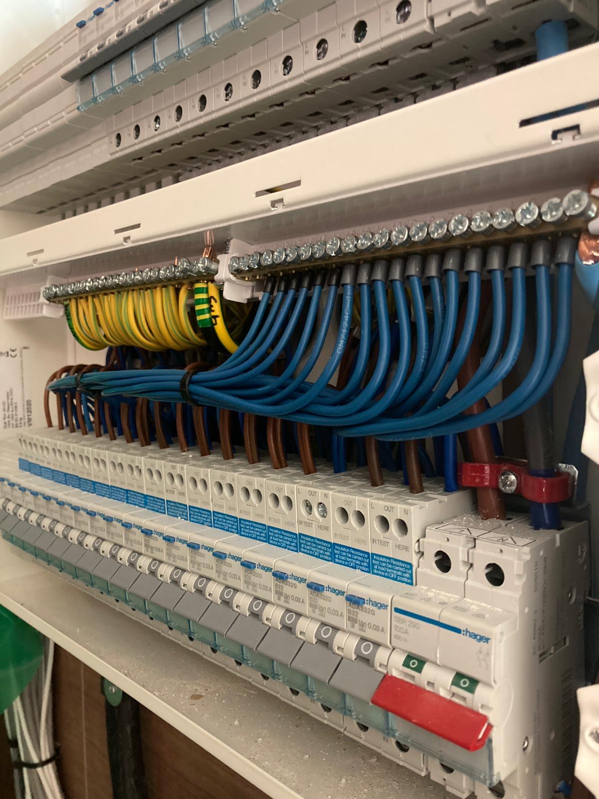 A large distribution board with rows of breakers and blue tails