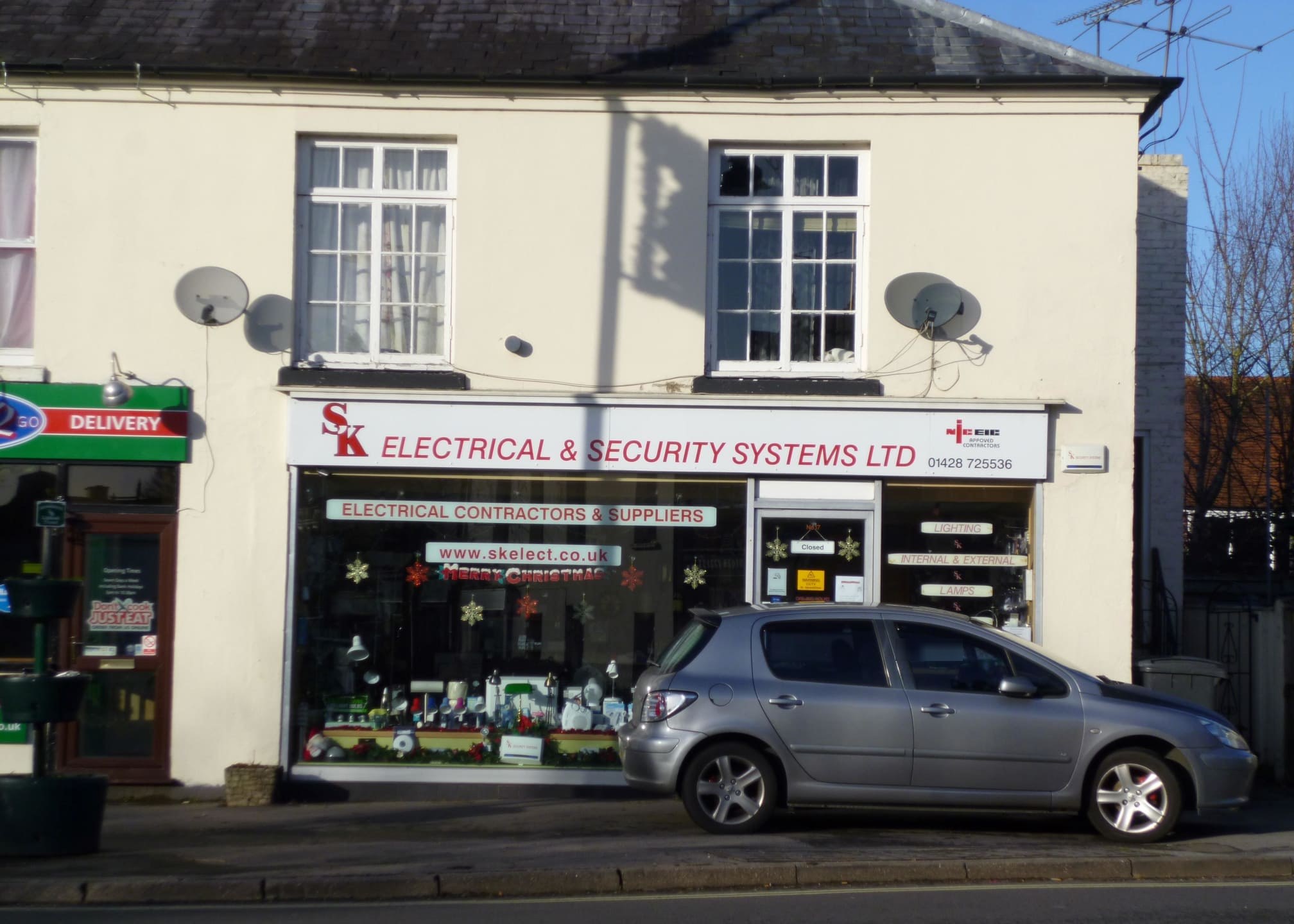 The SK Electrical & Security Systems shop on Midhurst Road, with the red sign and NICEIC badge