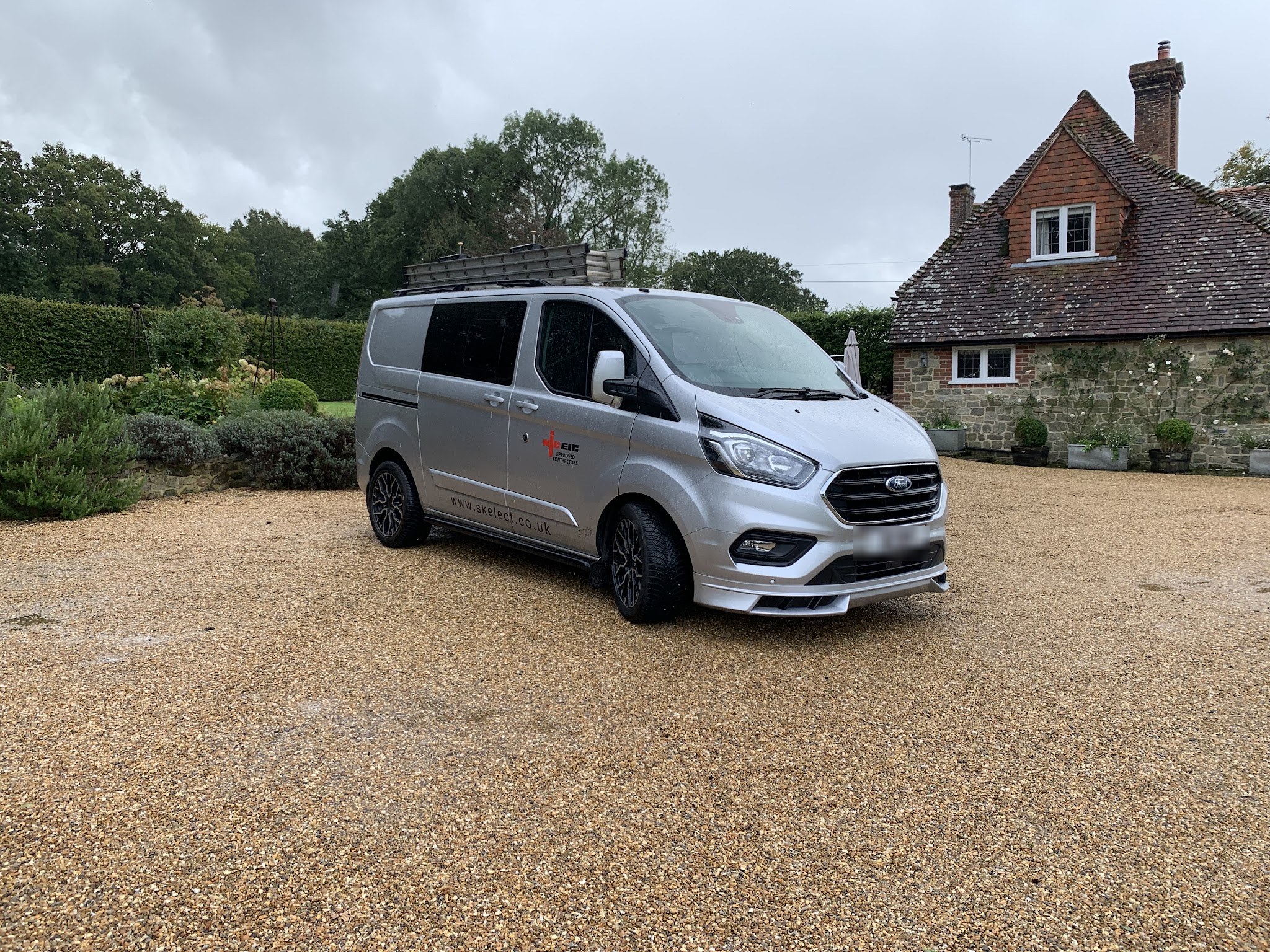 A silver SK Electrical van with NICEIC Approved Contractors livery on a gravel drive